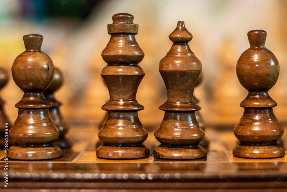 Chess pieces on board. King and Queen surrounded by bishops symbolizing royalty Chess pieces on board. King and Queen surrounded by bishops symbolizing royalty