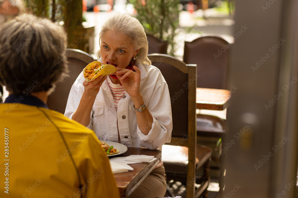 Woman eating a taco in the street cafe. Woman eating a taco in the street cafe.