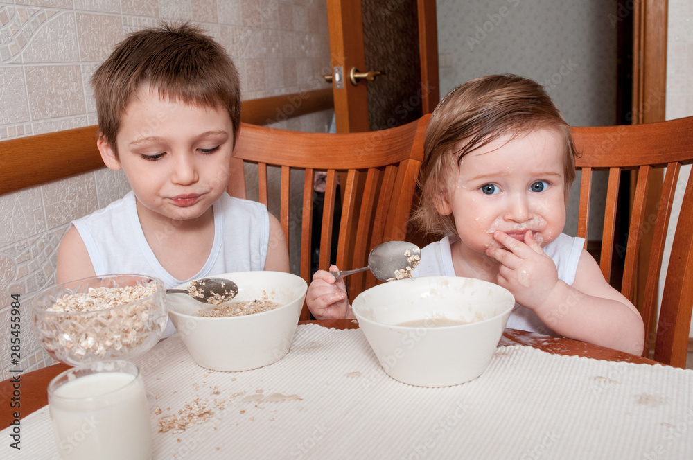 Two happy children having breakfast in kitchen at table