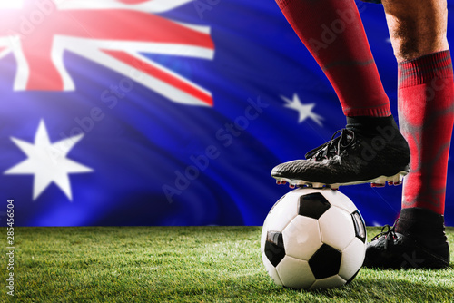 Close up legs of Australia football team player in red socks, shoes on soccer ball at the free kick or penalty spot playing on grass.