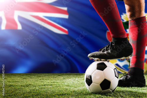 Close up legs of Cayman Islands football team player in red socks, shoes on soccer ball at the free kick or penalty spot playing on grass. © sezerozger
