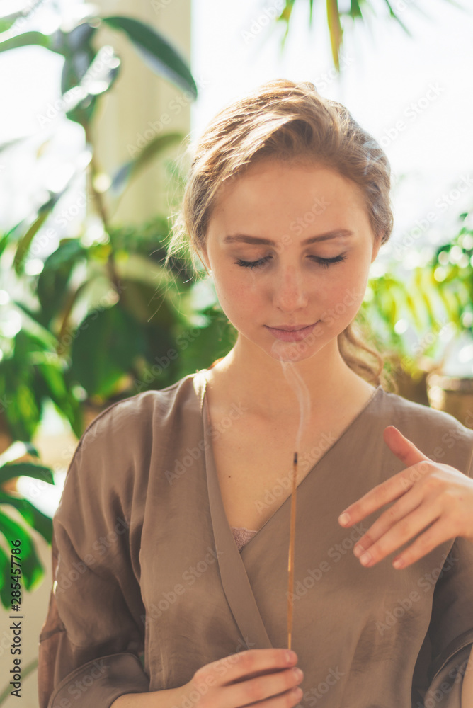 A young beautiful girl holds a smoking aromatic stalk in her hands. Aromatherapy, meditation, healthy life concept. A young beautiful girl holds a smoking aromatic stalk in her hands. Aromatherapy, meditation, healthy life concept.