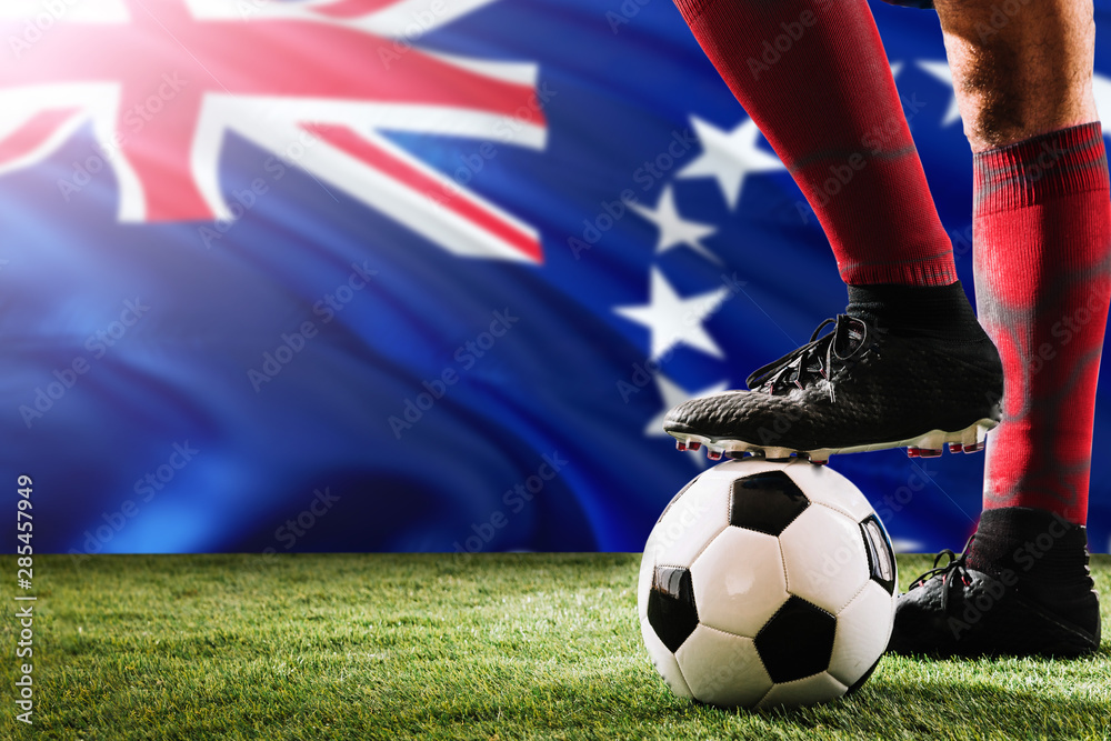 Close up legs of Cook Islands football team player in red socks, shoes on soccer ball at the free kick or penalty spot playing on grass.