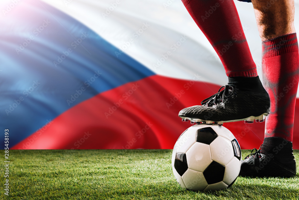 Close up legs of Czech Republic football team player in red socks, shoes on soccer ball at the free kick or penalty spot playing on grass.