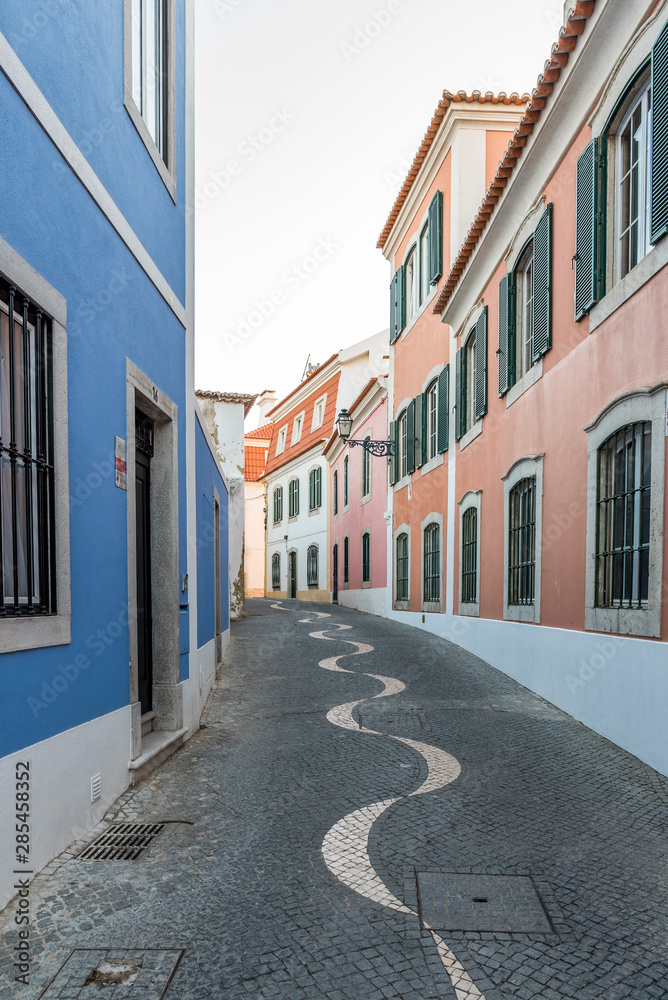 Narrow cobblestone alley between colourful stone houses in Cascais, Portugal
