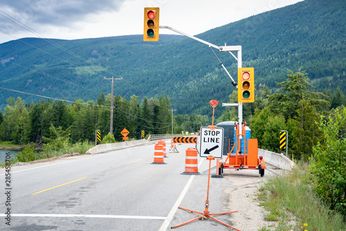 Traffic lights, cones and barriers at the beginning of a construction site along a mountain road on a cloudy summer day photo