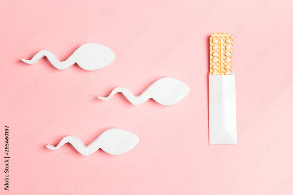 Female oral contraceptive pills blister in the way of sperm movement on pink background. - obrazy, fototapety, plakaty 