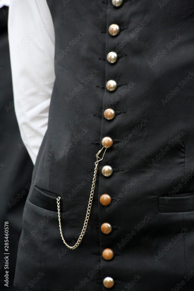 Men black vest with many golden buttons and a chain.