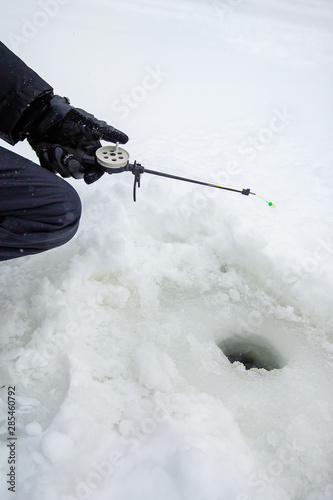 Close up of a ricky fisherman with a fishing rod. Ice and fishing rod for winter fishing. Winter fishing. Small catch of fish. photo