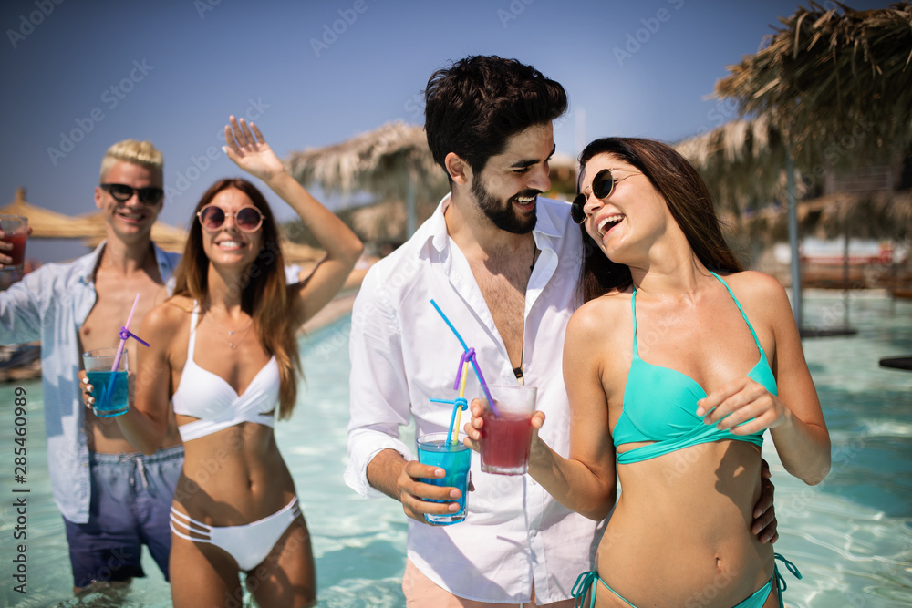 Group of happy friends having fun dancing at swimming pool outdoors