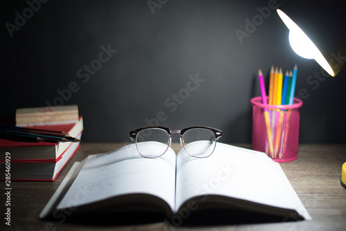 Reading table at night, Glasses placed on open book, And lighting from lamps, Copy-space