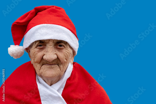 Very old woman 90 years old Mrs Claus with funny expression. Grand-mother or elderly woman with big happy smile wearing Santa Claus hat perfect for Christmas and seniors themes.
