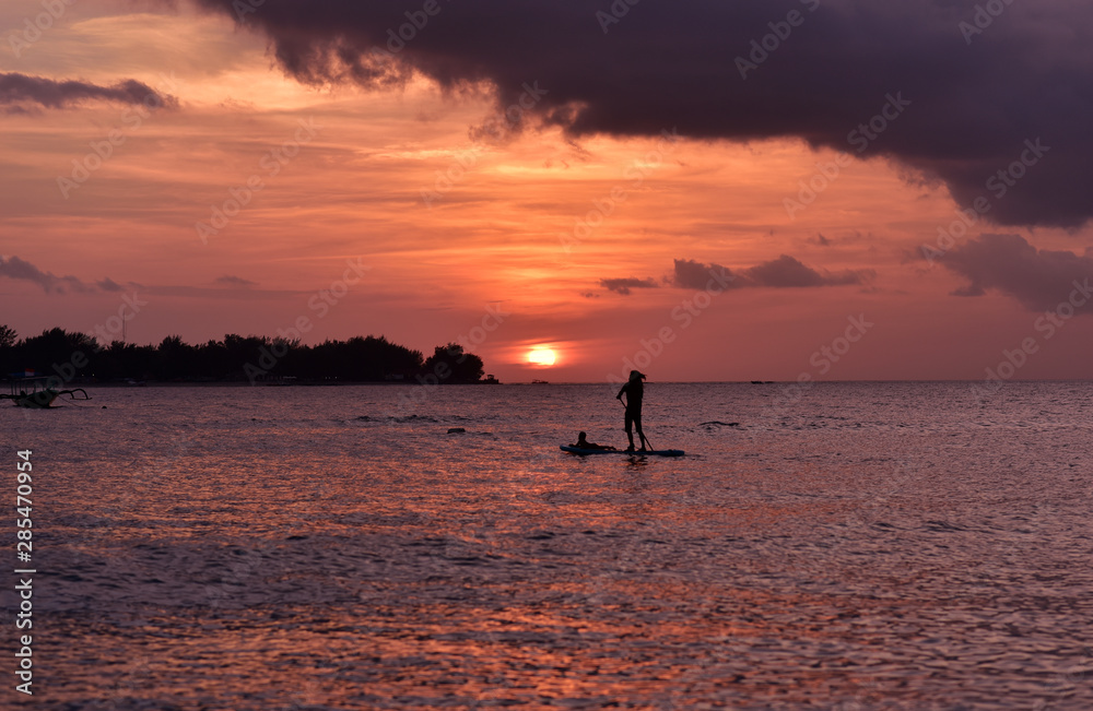 Sihouette of the indonesian man paddling between the islands Gili Meno and Gili trawangan in sunrise, Lombok, Indonesia
