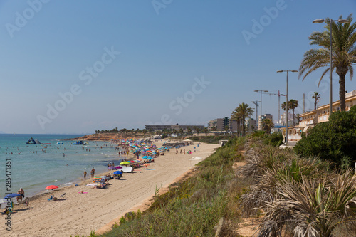 Mil Palmeras beach Costa Blanca Spain with palm trees and holidaymakers with parasols in beautiful summer weather © acceleratorhams