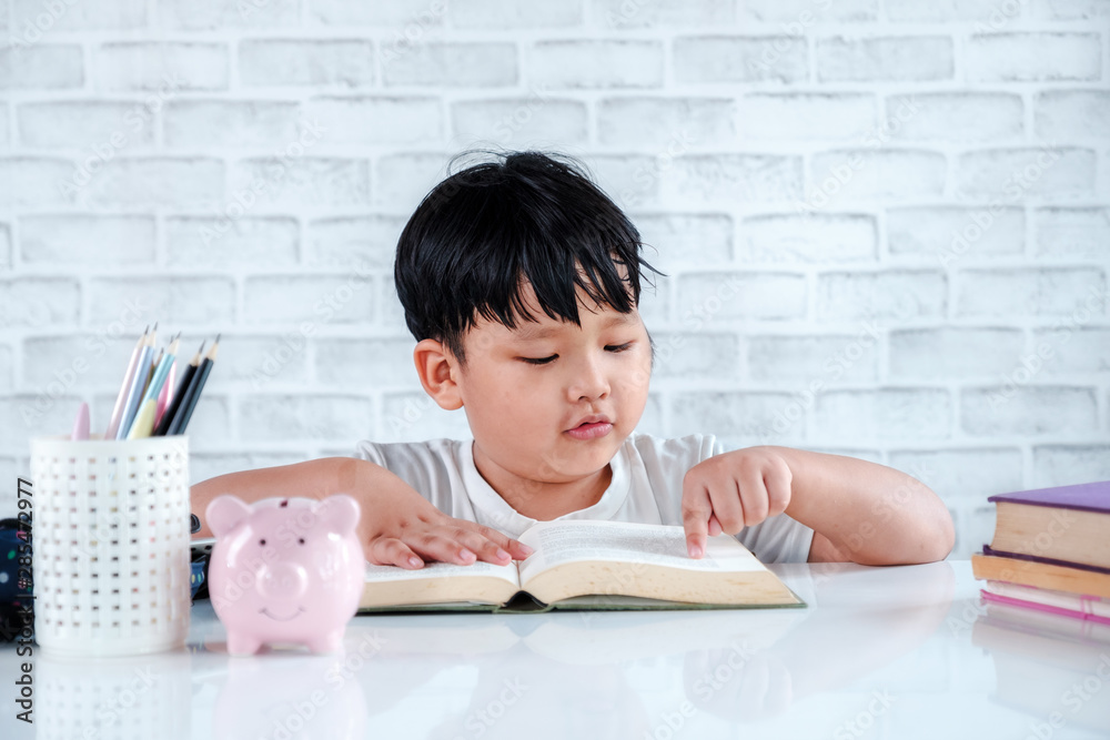 © Satori Studio - Asian little boy reading a book on white desk in home. Back to school concept © Satori Studio - Asian little boy reading a book on white desk in home. Back to school concept