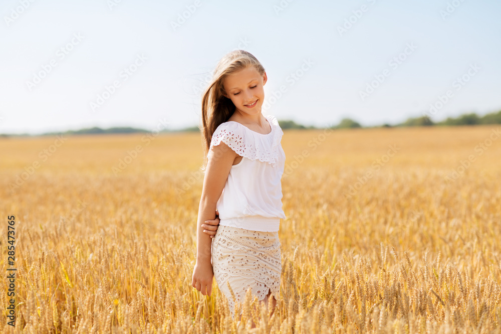nature, harvest and people concept - smiling young girl on cereal field in summer nature, harvest and people concept - smiling young girl on cereal field in summer