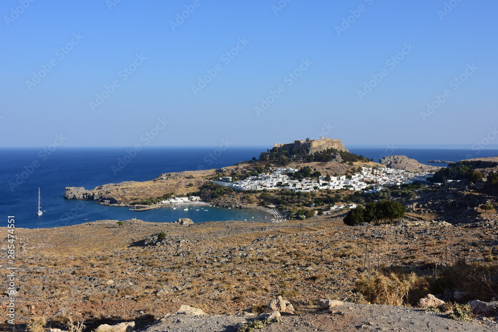 Rhodes city view of Lindos and the ancient acropolis and the beautiful blue waters of the Aegean Sea.