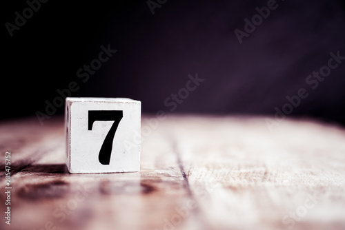 Number 7 isolated on dark background- 3D number seven isolated on vintage wooden table photo