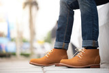 Fashion men's legs in blue jeans and brown ankle boots for man collection.