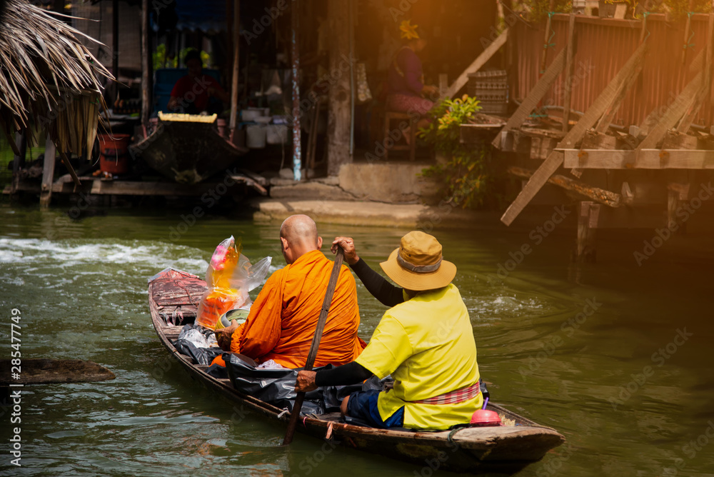 floating Dawning, Thai monk paddle the boat receiving food on canal The tradition of making merit to monks morning floating Dawning, Thai monk paddle the boat receiving food on canal The tradition of making merit to monks morning