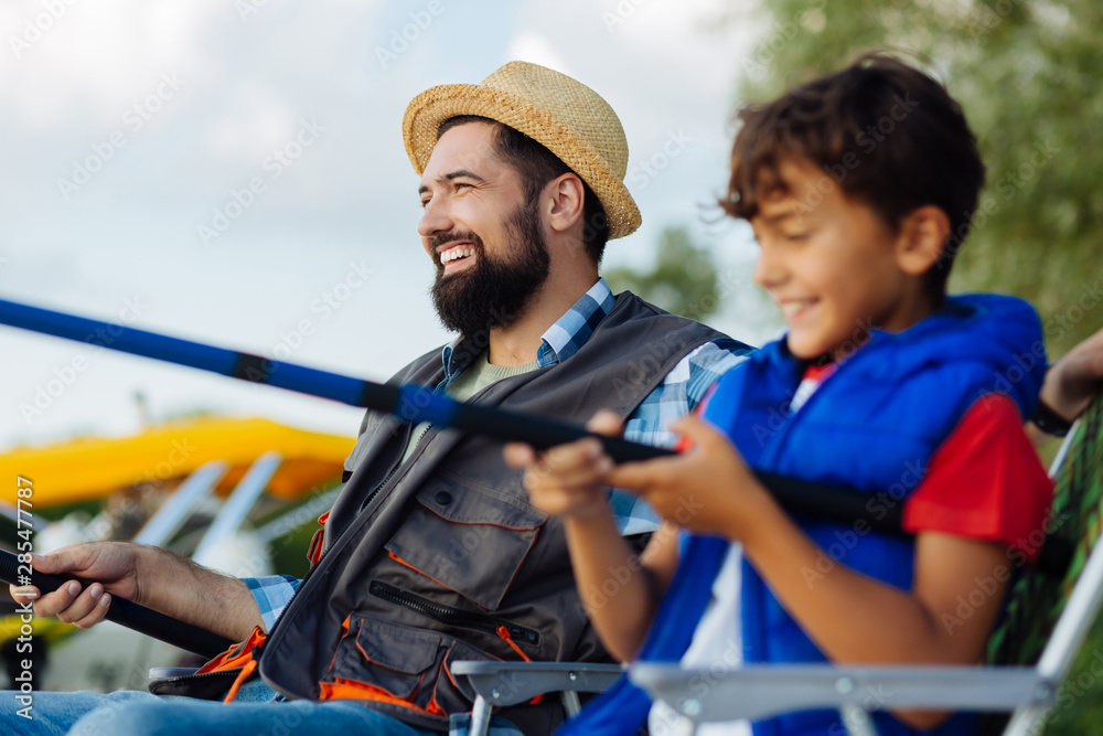 Happy father and son feeling involved in fishing together