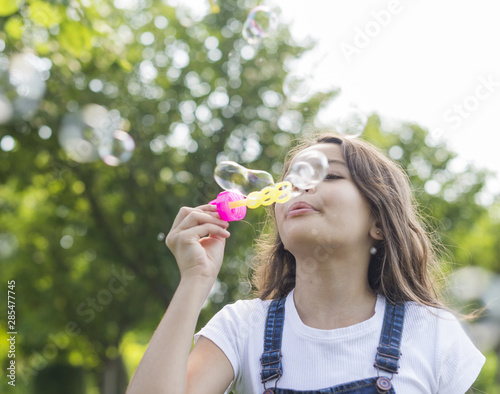 Low angle girl making soap bubbles