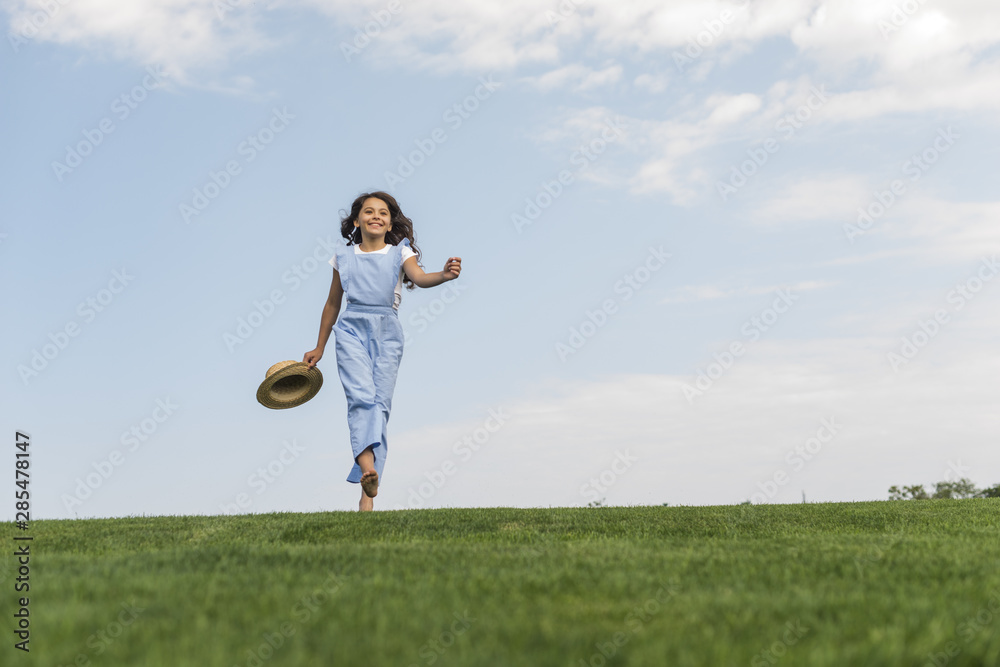 Long shot girl walking barefoot on grass