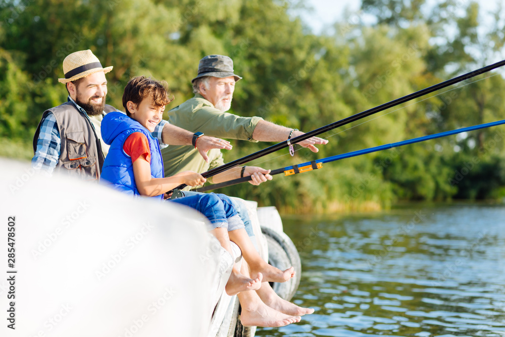 Boy feeling happy while fishing with father and grandfather Boy feeling happy while fishing with father and grandfather