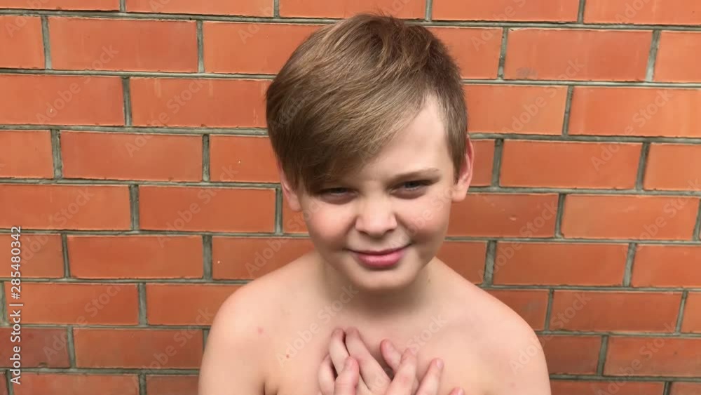 The boy makes grimaces on a background of a brick wall The boy makes grimaces on a background of a brick wall