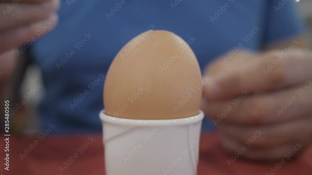 Healthy Breakfast. Man Cleans and Eats a Soft Boiled Egg. Slow Motion. Closeup. Male Hands is Shelling Chicken Eggs. Boiled Egg on a Stand. 4K UHD
