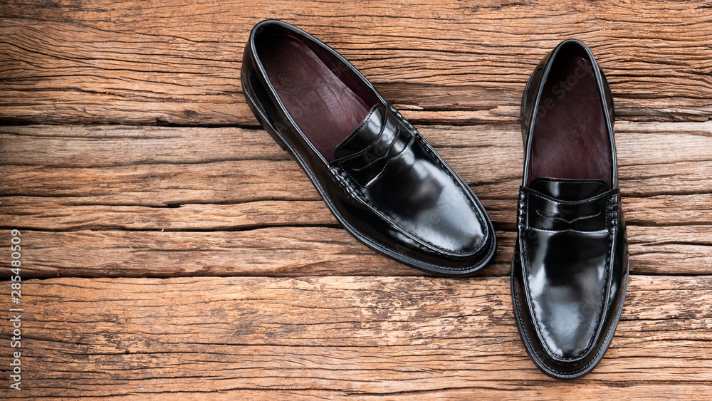 Men fashion of penny loafer black shoes on wooden background. Top view Men fashion of penny loafer black shoes on wooden background. Top view