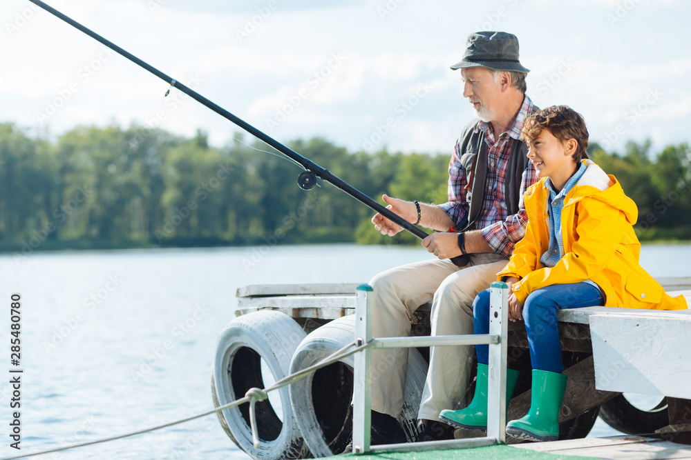Bearded mature man fishing sitting near grandson Bearded mature man fishing sitting near grandson