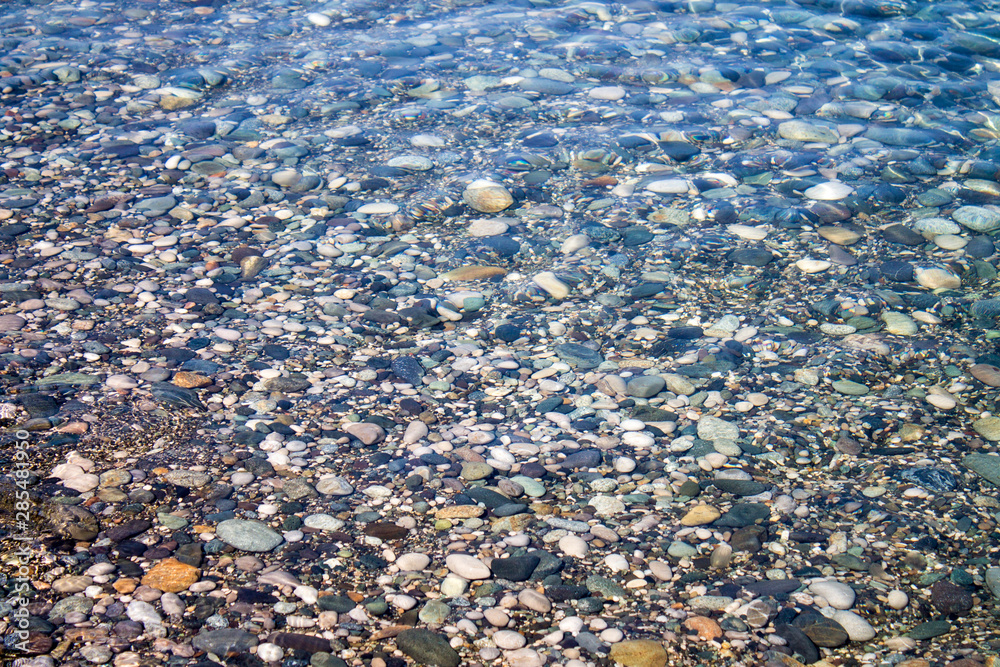 Sea stones in sea water. Pebbles under water. The view from the top. Nautical background. Clean sea water. Transparent sea. Sea stones in sea water. Pebbles under water. The view from the top. Nautical background. Clean sea water. Transparent sea.