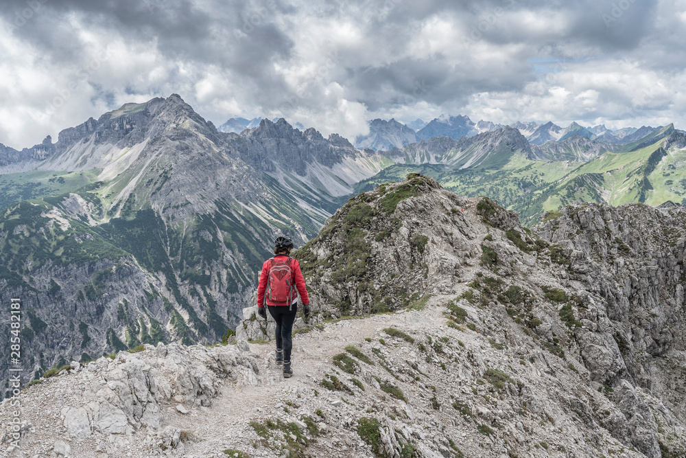 nice and active senior woman approaching the summit of Litnis Schrofen during a bike and hike adventure in the Tannheim Valley, Tirol Austria