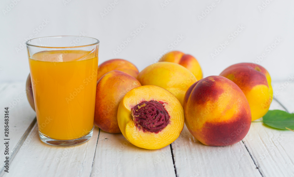 Delicious and juicy peach (nectarina) with glass of juice on white wooden table Delicious and juicy peach (nectarina) with glass of juice on white wooden table