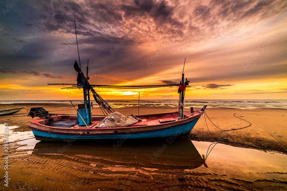 Beautiful sunrise over an old wooden fishing boat on a pebble beach