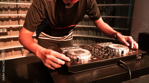 Obraz na plátně portrait of a male with hat Disc jockey or dj playing turn table, mixer, music