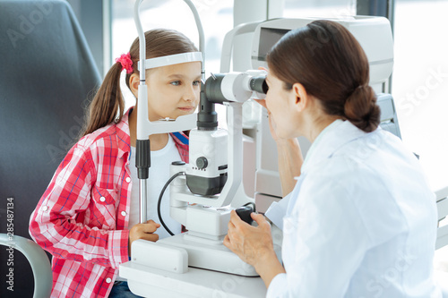 Tableau sur toile Professional female doctor looking into the special device