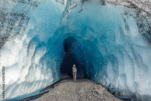 Fotografia, Obraz A woman walking into an ice cave in Alaska
