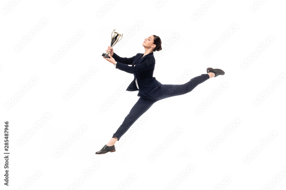 happy businesswoman holding trophy cup while jumping in dance isolated on white