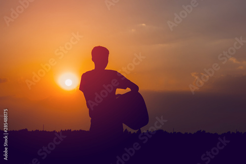 The silhouette of a guitarist who holds a guitar and has a sunset, silhouette concept.