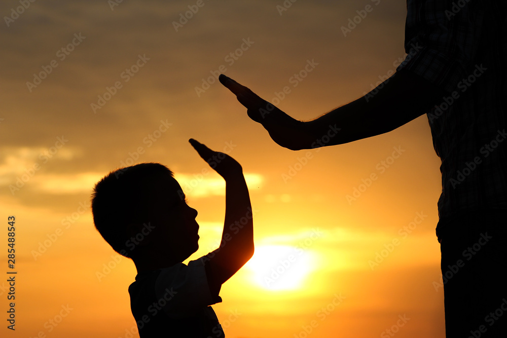 silhouette parent holds the hand of a  child