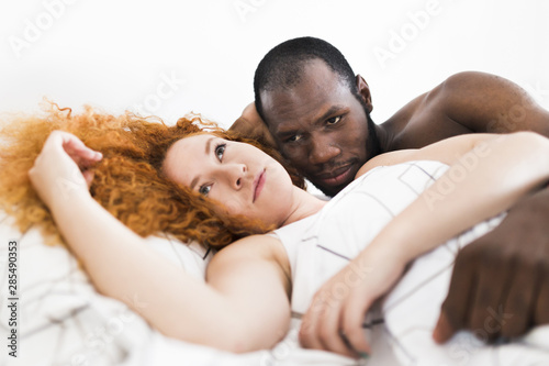 Intimate moment of interracial couple in bed