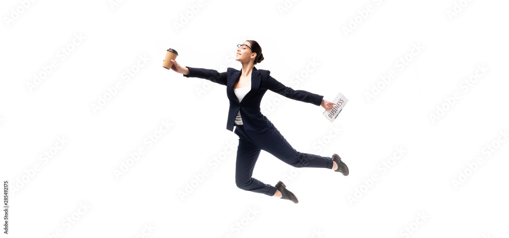 panoramic shot of beautiful businesswoman holding newspaper and paper cup while levitating isolated on white