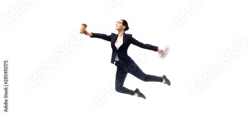 panoramic shot of beautiful businesswoman holding newspaper and paper cup while levitating isolated on white