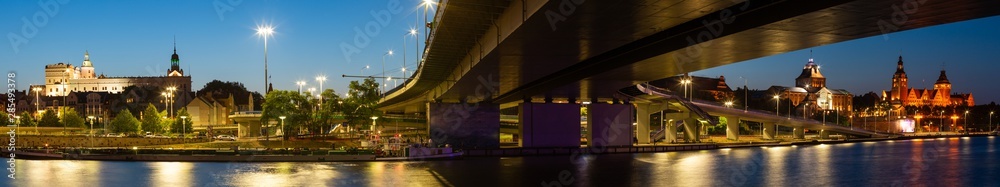 Szczecin. Night panorama of the illuminated historic city seen behind the river.