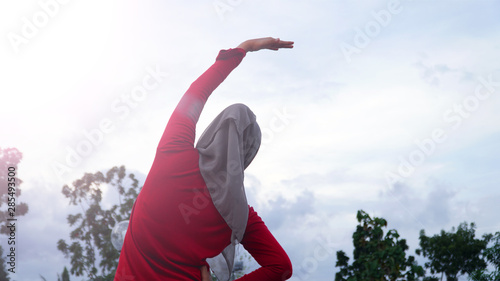 back view of hijab woman doing stretching and warming up her body before running