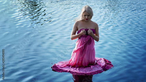 a beautiful girl with white hair in a pink dress is standing in the lake