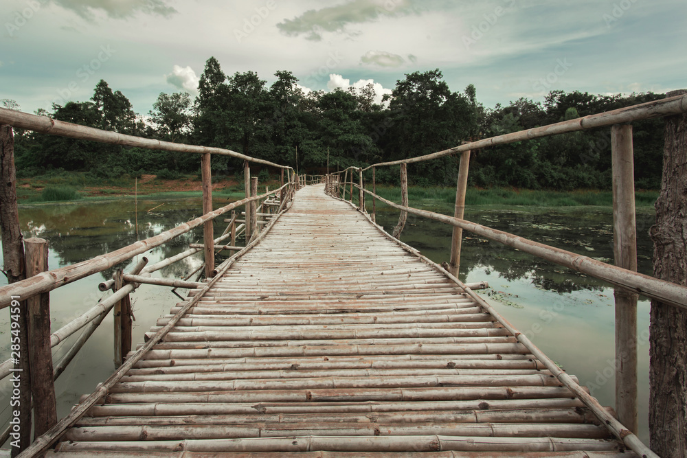Wooden bridge made of bamboo across the water. The concept for the building project.