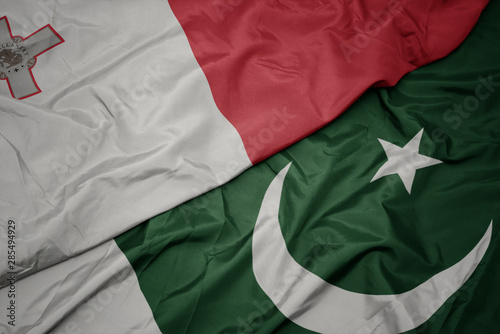 waving colorful flag of pakistan and national flag of malta.